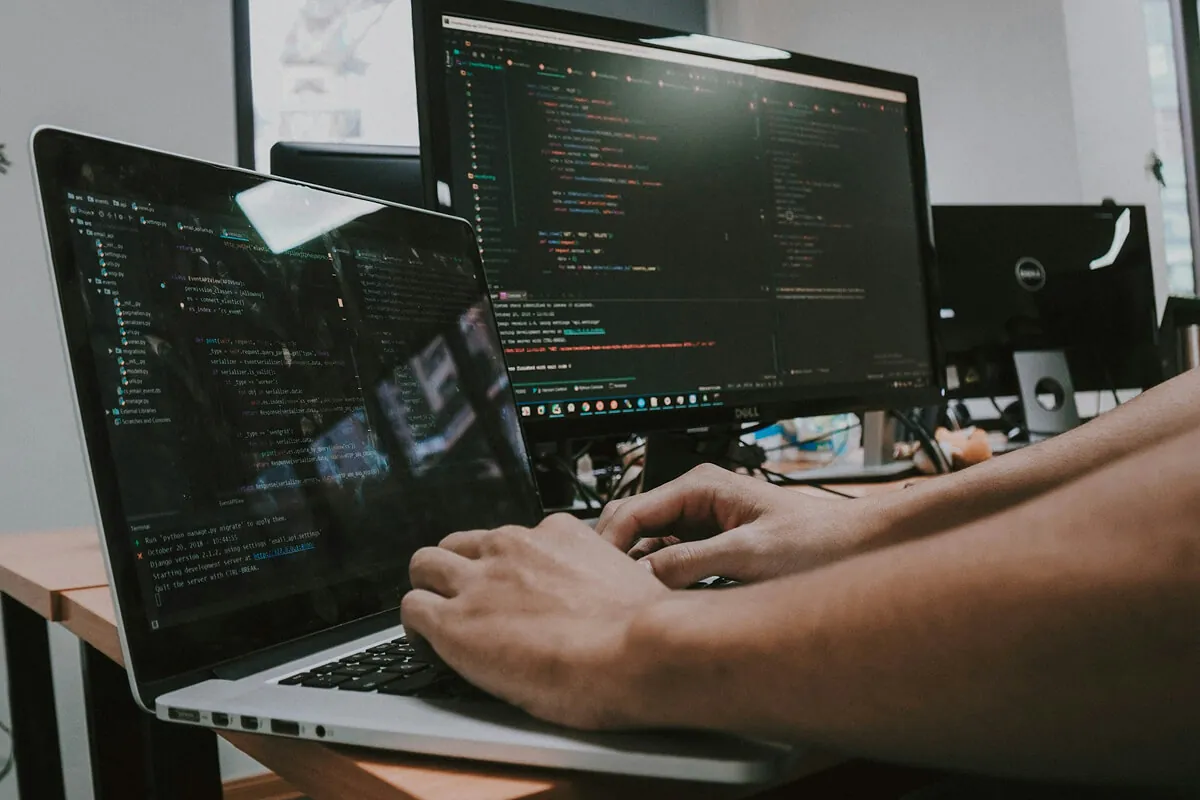 Developer working across a laptop and monitor while building an AI product