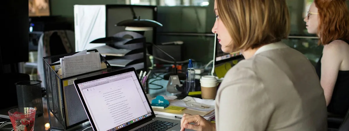 Women working on laptops in a modern office workspace.