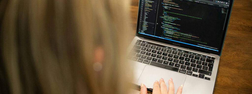 An over-the-shoulder shot of a person using a code editor on a MacBook Pro.
